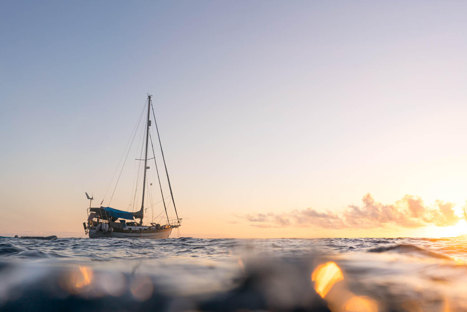 Sailing boat at anchor in sunset light from water level